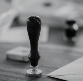 A wooden stamp sits on a wooden desk.